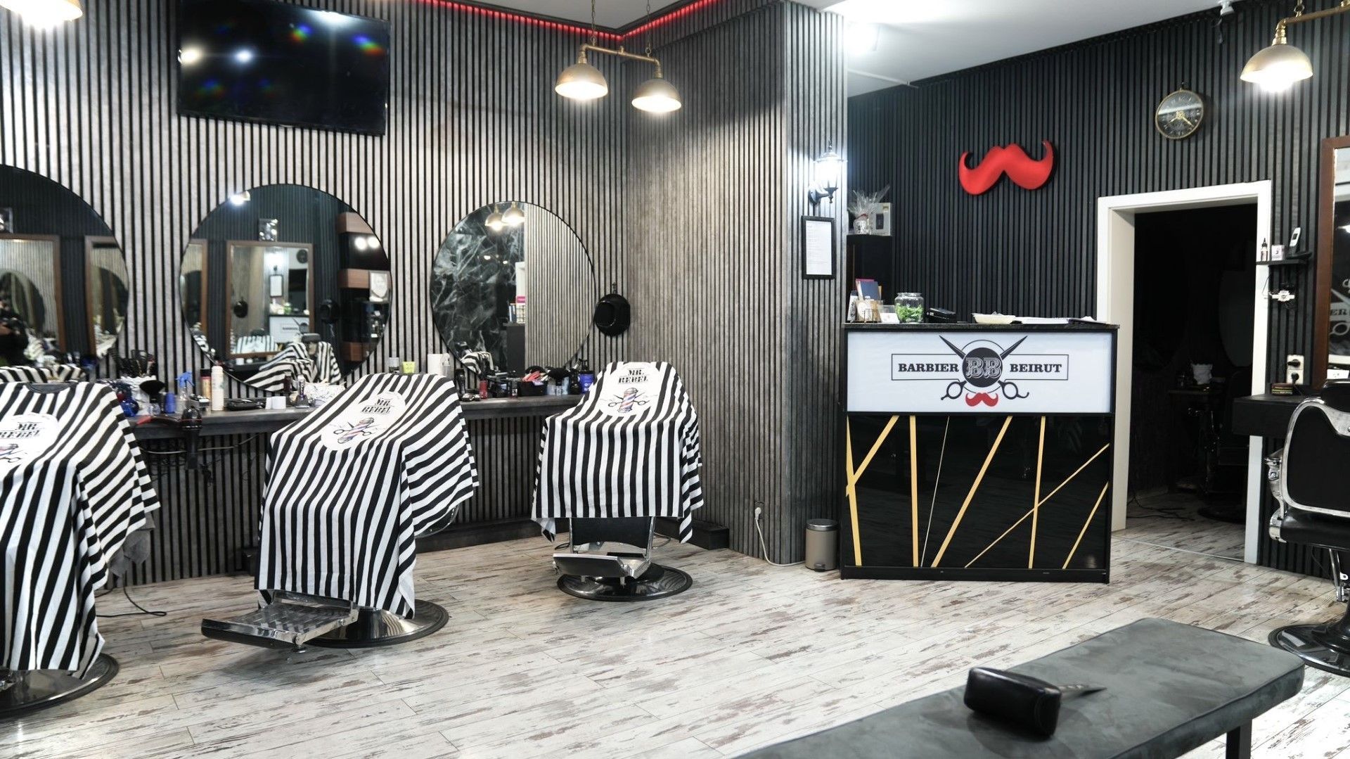 Der Salon von innen mit Barberstühlen, Spiegeln und gestreiften Umhängen